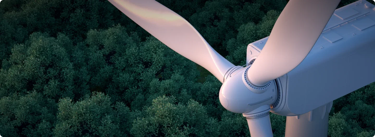 A close-up view of a wind turbine rotor and blades seen from above, with a dense forest canopy visible below.