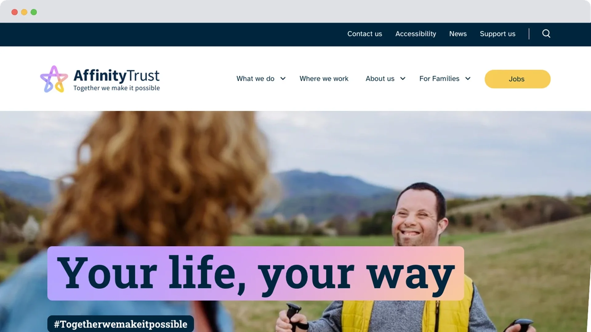 A man with Down’s syndrome smiles as he walks outdoors using walking poles, looking towards a woman in the foreground. A banner over the image reads: “Your life, your way”.