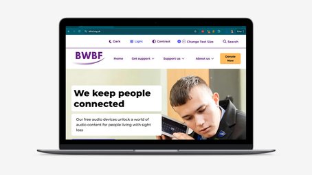 A laptop on a light grey background displaying the homepage of BWBF