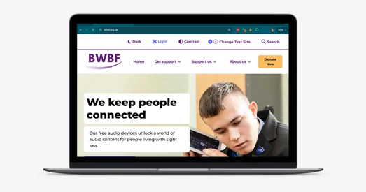 A laptop on a light grey background displaying the homepage of BWBF