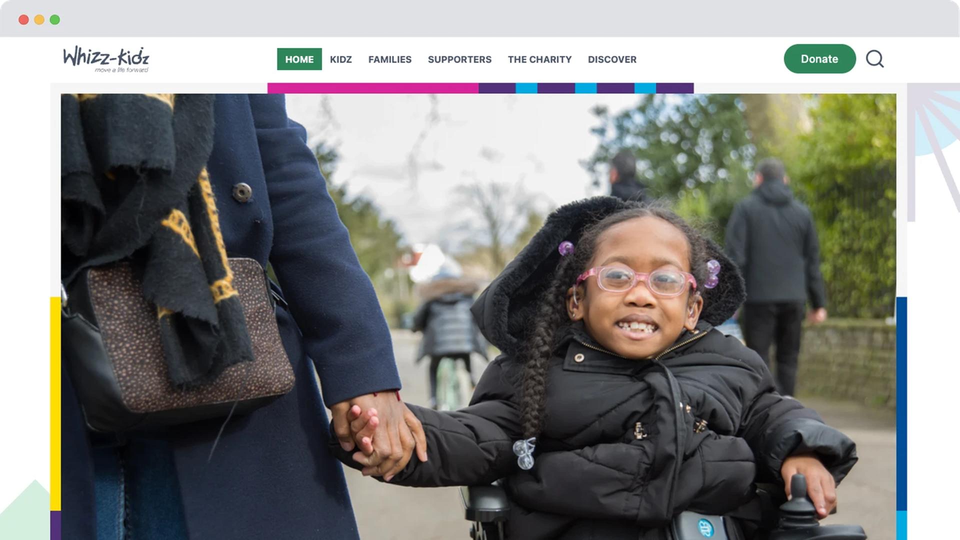 An earlier version of the Whizz-Kidz homepage showing a young girl in a wheelchair holding hands with an adult, smiling on a paved path.