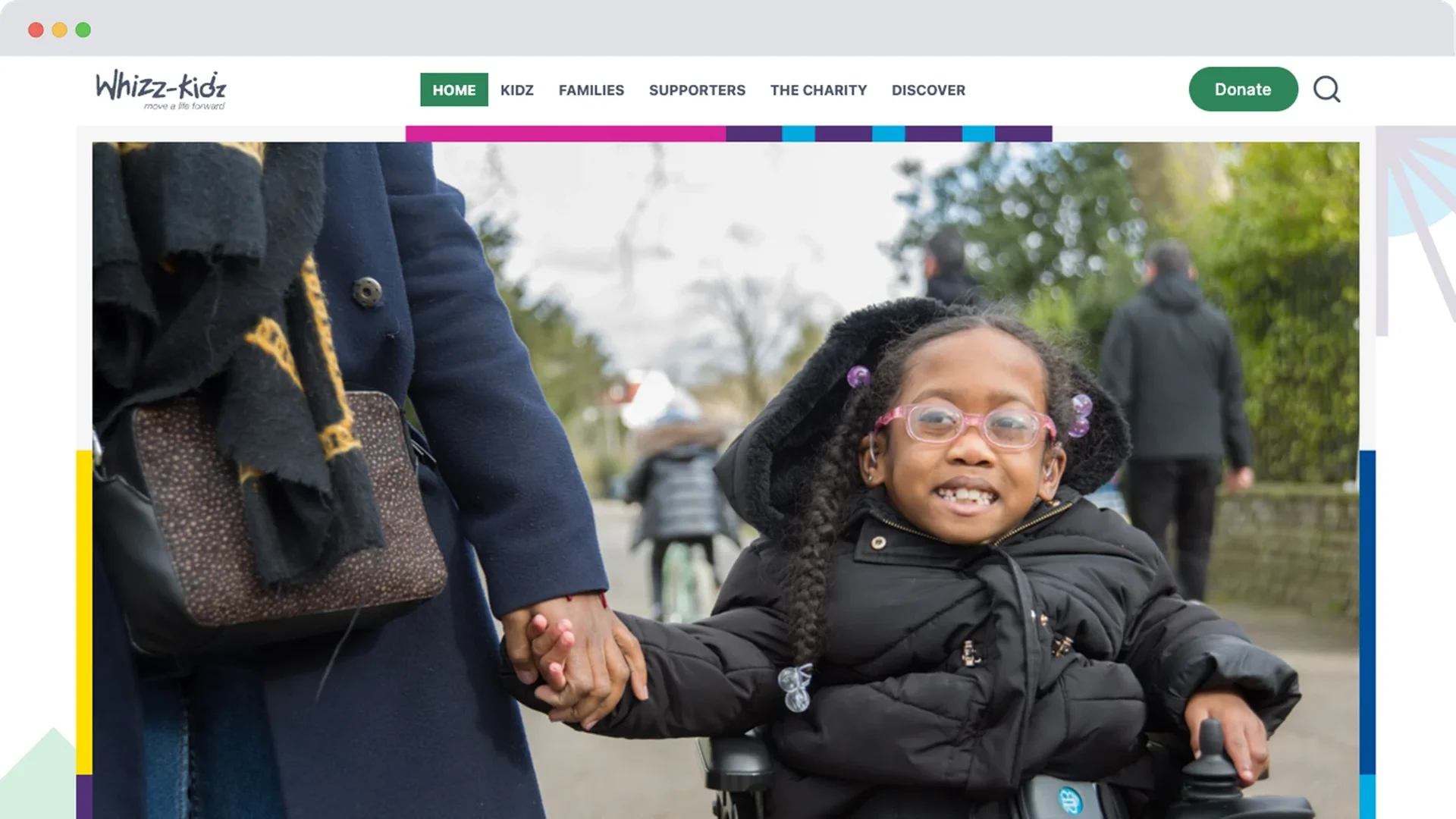 An earlier version of the Whizz-Kidz homepage showing a young girl in a wheelchair holding hands with an adult, smiling on a paved path.