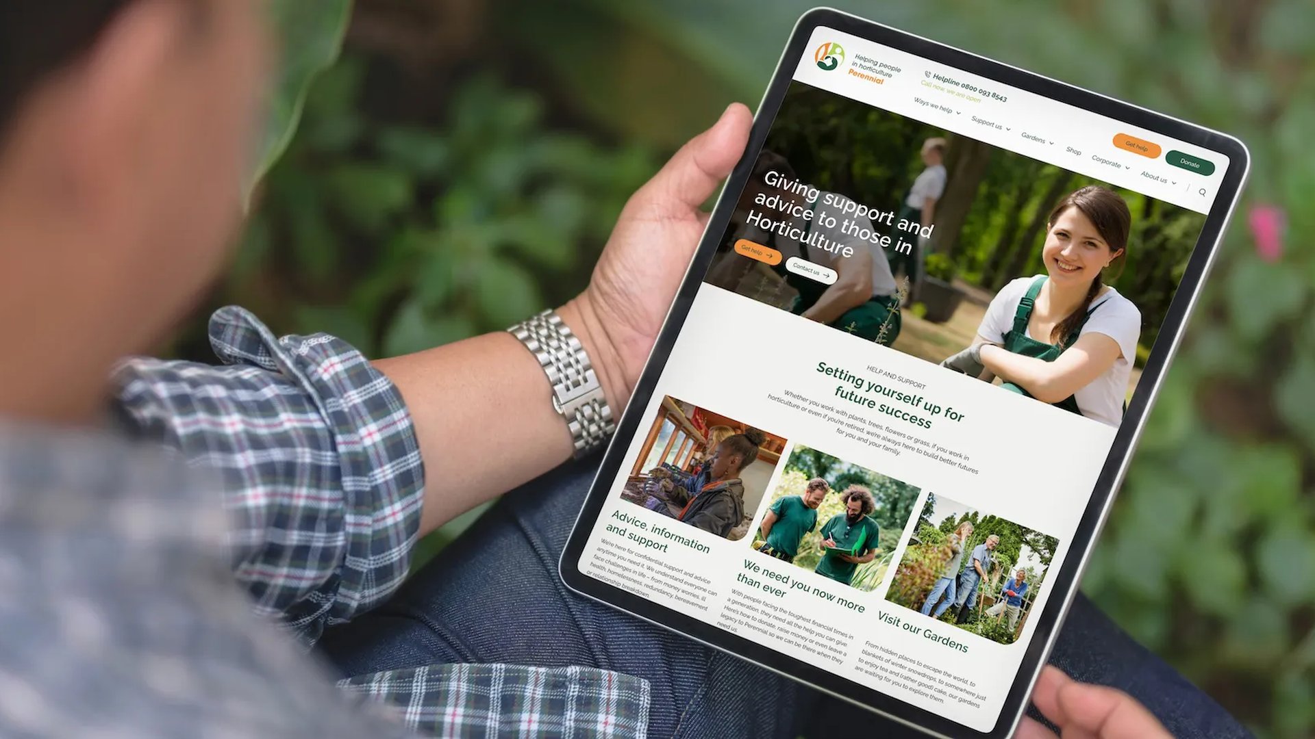 Person holding a tablet outdoors, browsing the Perennial website which offers support and advice for people in horticulture.