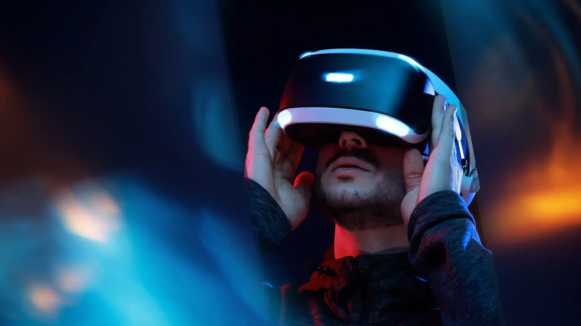 Close-up of a person wearing a virtual reality headset, immersed in a digital experience with a vibrant blue and orange-lit background.