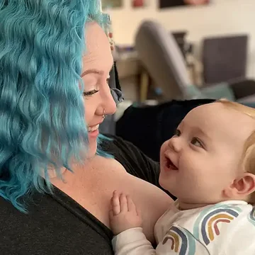 Melissa looking at her baby with a joyful smile, both making eye contact in a tender moment at home.