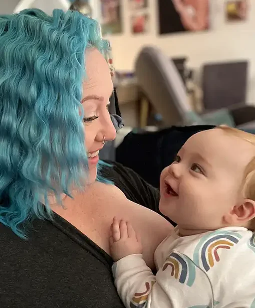 Melissa looking at her baby with a joyful smile, both making eye contact in a tender moment at home.